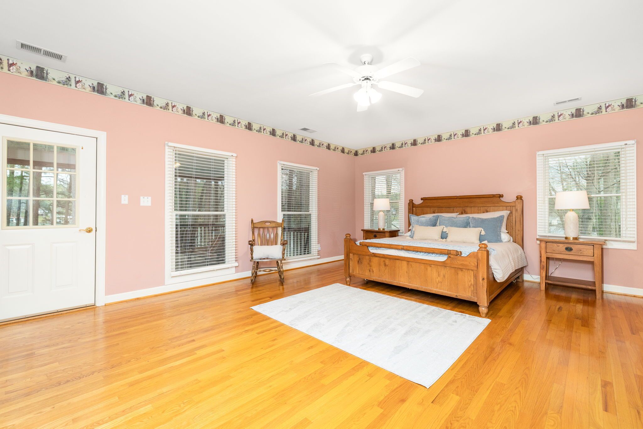 A bedroom with a wooden bed, white walls, and a ceiling fan.