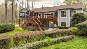 A two-story house with a covered porch, a staircase, and a well-maintained garden. - Lakefront, Dock, Kayaks, Games, Firepit, Fireplace (Littleton)