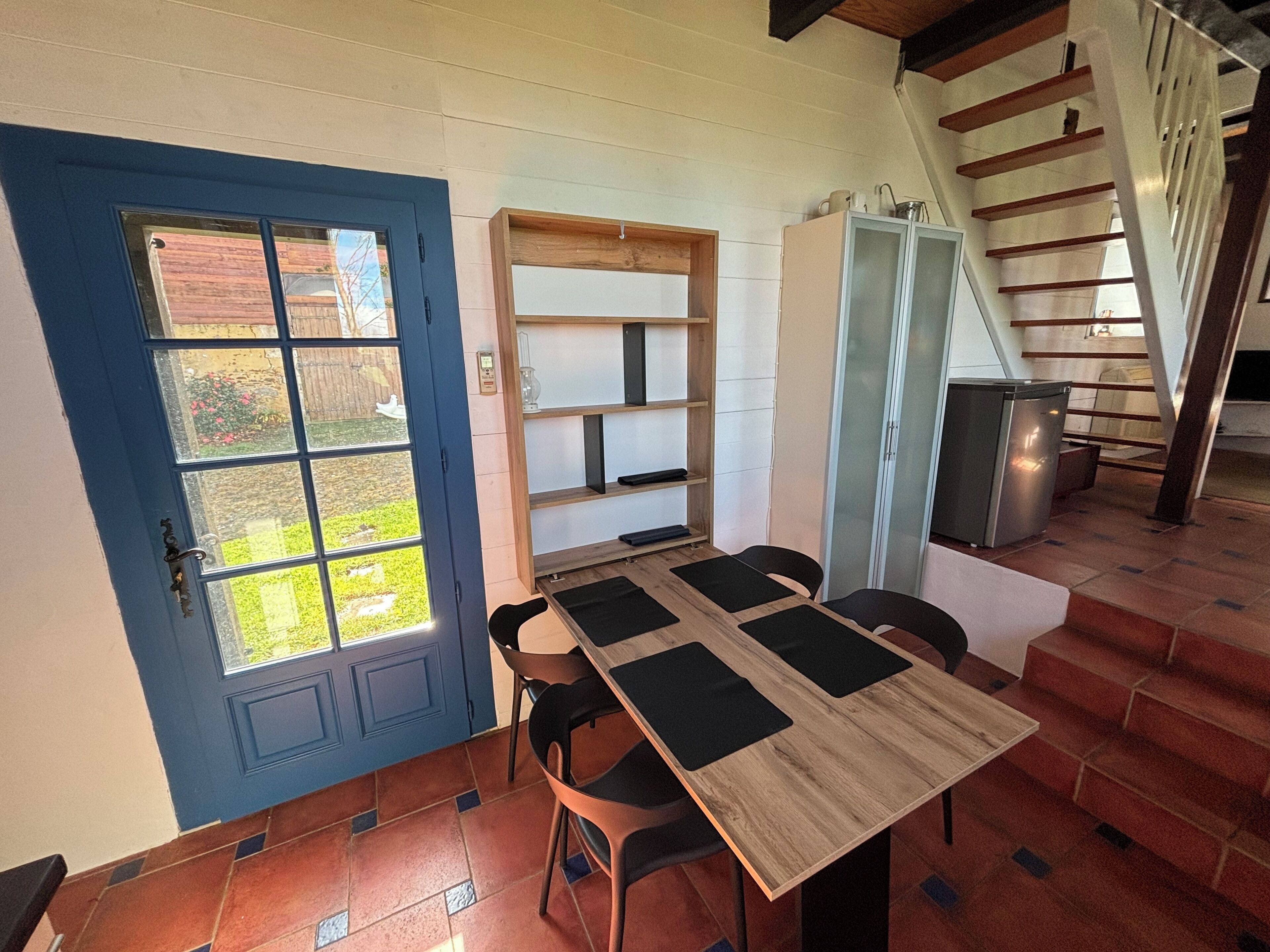 A dining area with a table and chairs, a blue door, and a staircase.