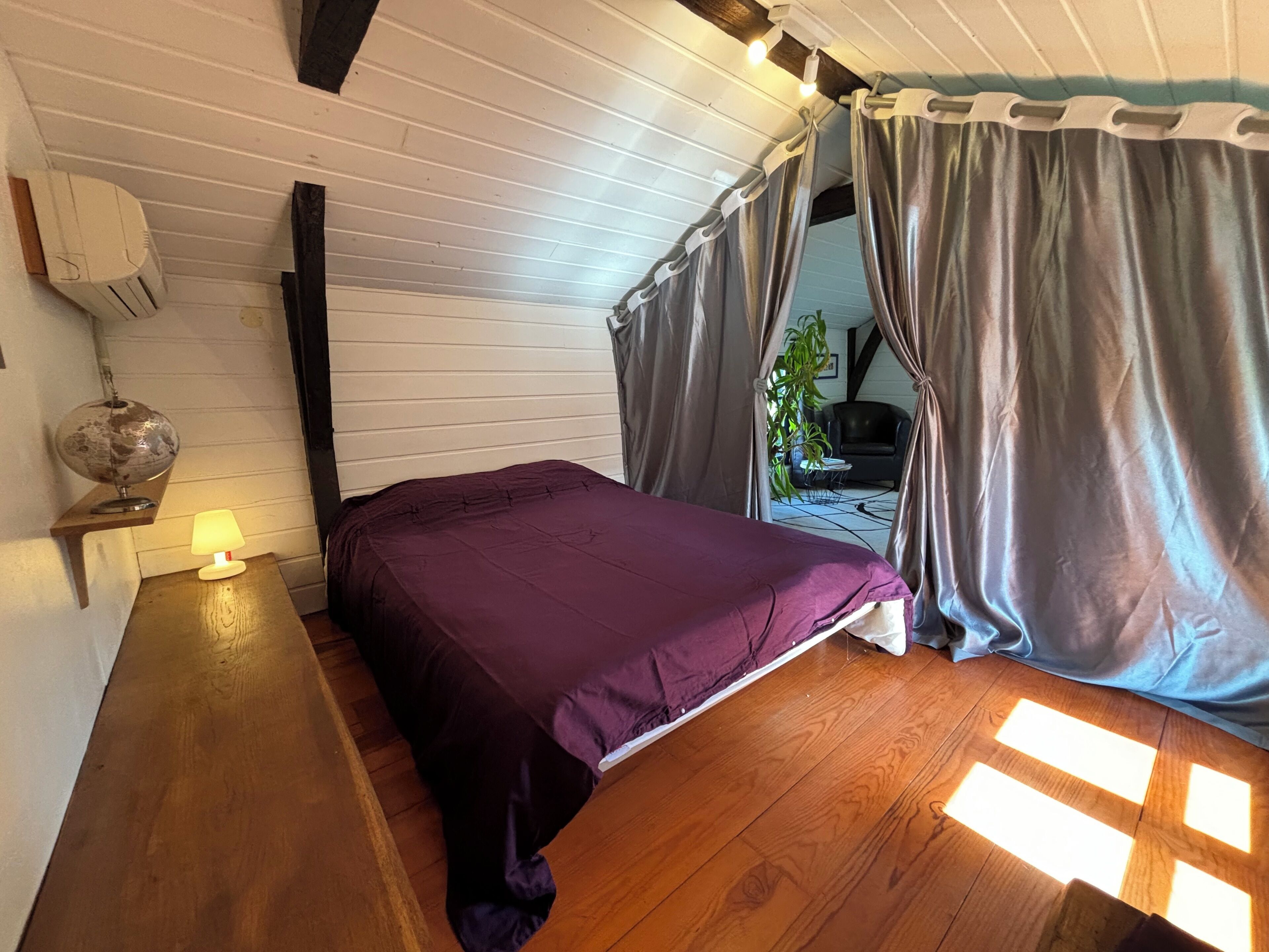 A room with a bed, a lamp, a globe, and a plant.