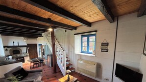 Ein Wohnzimmer mit Sofa, Couchtisch, Fernseher, Kamin und einer Treppe, die zur Küche führt.