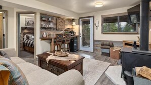 A cozy living room with a fireplace, a dining area, and a kitchen visible through an open door.