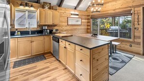 A modern kitchen with wooden cabinets, a dishwasher, and a large island.