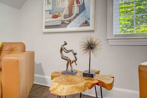 A room with a brown leather sofa, a wooden coffee table with a sculpture and a decorative piece, and a framed picture on the wall. - Downtown Oasis Second-Floor Condo (Princeton)