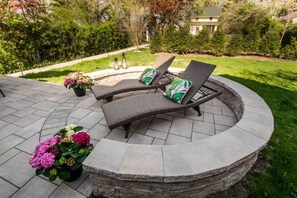 Een rond terras van natuursteen met twee loungesteilen en een potplant.
