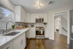 A modern kitchen with white cabinetry, a stainless steel oven, and a microwave. - Downtown Oasis Second-Floor Condo (Princeton)