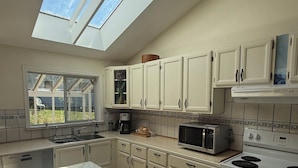 A kitchen with skylights, a sink, cabinets, a microwave, and a stove. - 2 Bedroom Semi-Waterfront Cottage in Vesuvius, Salt Spring Island (Salt Spring Island)