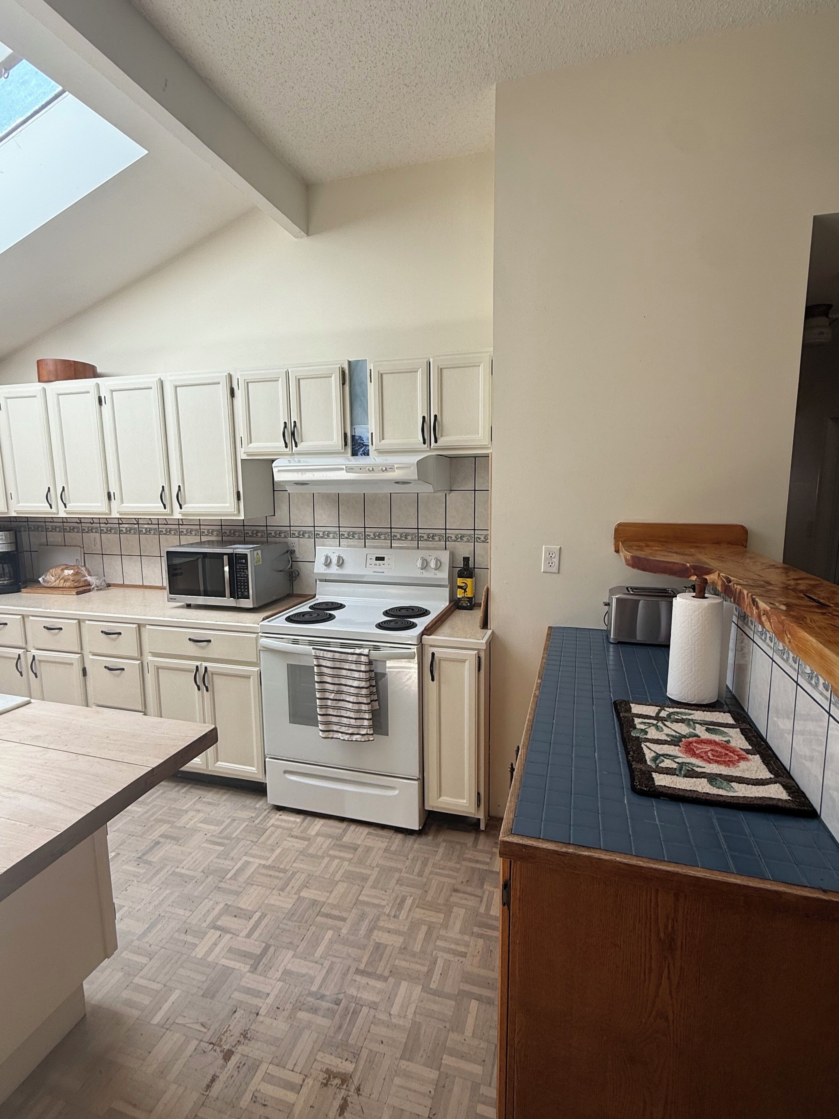 A kitchen with white cabinets, a stove, a microwave, and a toaster.