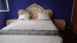 A bedroom with a tufted headboard, two bedside tables, and a bed with a patterned bedspread. - Apartment M15 (Luanda)