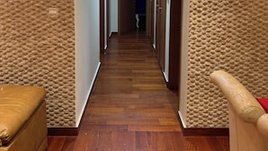 A hallway with wooden flooring, textured walls, and doors leading to rooms. - Apartment M15 (Luanda)