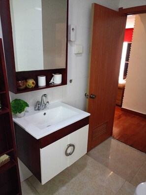 A bathroom with a white sink, a mirror, and a wooden door.