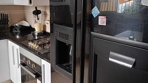 A kitchen with white cabinets, a black refrigerator, a stove, and a microwave. - Apartment M15 (Luanda)