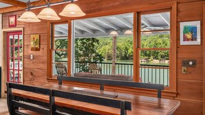 A wooden interior with a bench, large windows, and a view of greenery.