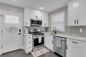 Une cuisine moderne avec des armoires blanches, une cuisinière en acier inoxydable, un four à micro-ondes et un lave-vaisselle.