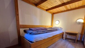 Un simple lit en bois avec une tête de lit, une table de chevet et une applique murale ronde.