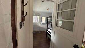 Kapea käytävä johtaa makuuhuoneeseen, jossa on kerrossänky, ja siinä on ovi, jossa on himmeä lasipaneeli, sekä naulakko koukuineen.