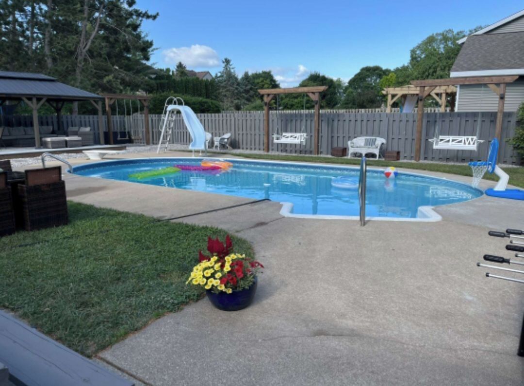 Un jardin avec une piscine, un toboggan et une terrasse en bois.