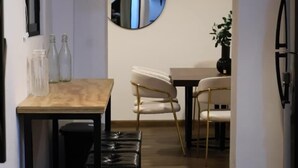 Un pasillo con piso de madera, un espejo redondo en la pared y una zona de comedor con mesa y sillas.