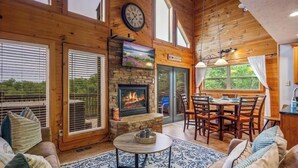 A wooden interior with a fireplace, dining area, and large windows. - New Listing! Cabin On The Lake, Hot Tub, Game Rm! (Sevierville)