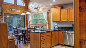 A wooden cabin interior with a kitchen, dining area, and large windows. - New Listing! Cabin On The Lake, Hot Tub, Game Rm! (Sevierville)