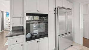 A kitchen with white cabinetry, a stainless steel refrigerator, and a built-in oven. - Beverly Hills Home Guest House & Hot Tub (Beverly Hills)