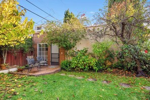 A backyard with a patio, a wooden fence, and a tree.