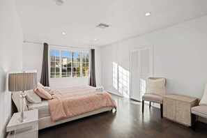 A bedroom with a bed, bedside table, lamp, chair, and a window with curtains.