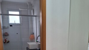 Casa de banho com sanita, lavatório e zona de duche.