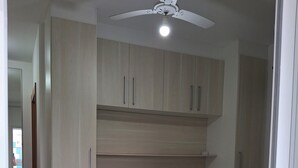 Quarto com cama, ventilador de teto e armários embutidos.