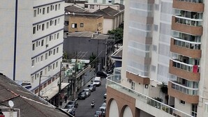 Um edifício de vários andares com um pátio central, varandas e vista para a rua.