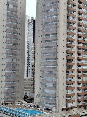 Un edificio de gran altura con varios balcones, piscina y un patio.