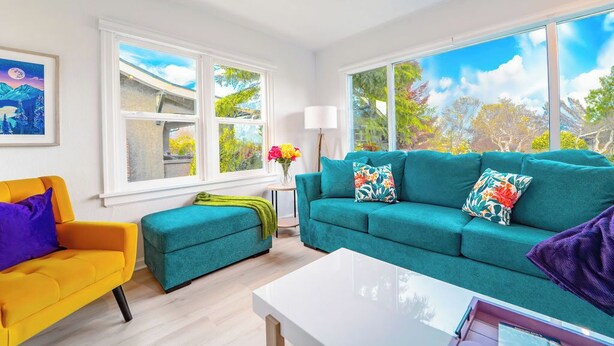 Una sala de estar con un sofá color turquesa, un sillón amarillo y una mesa de centro blanca.