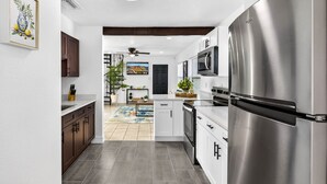 A modern kitchen with stainless steel appliances, white cabinetry, and a central island. - Pool Oasis -Near RJ Stadium, Hyde Park & Downtown (Tampa)