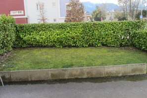 Une zone herbeuse bien entretenue, bordée d’une haie et d’un bord en béton.