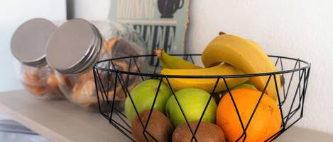 A wire basket containing fruits and a jar with a lid.