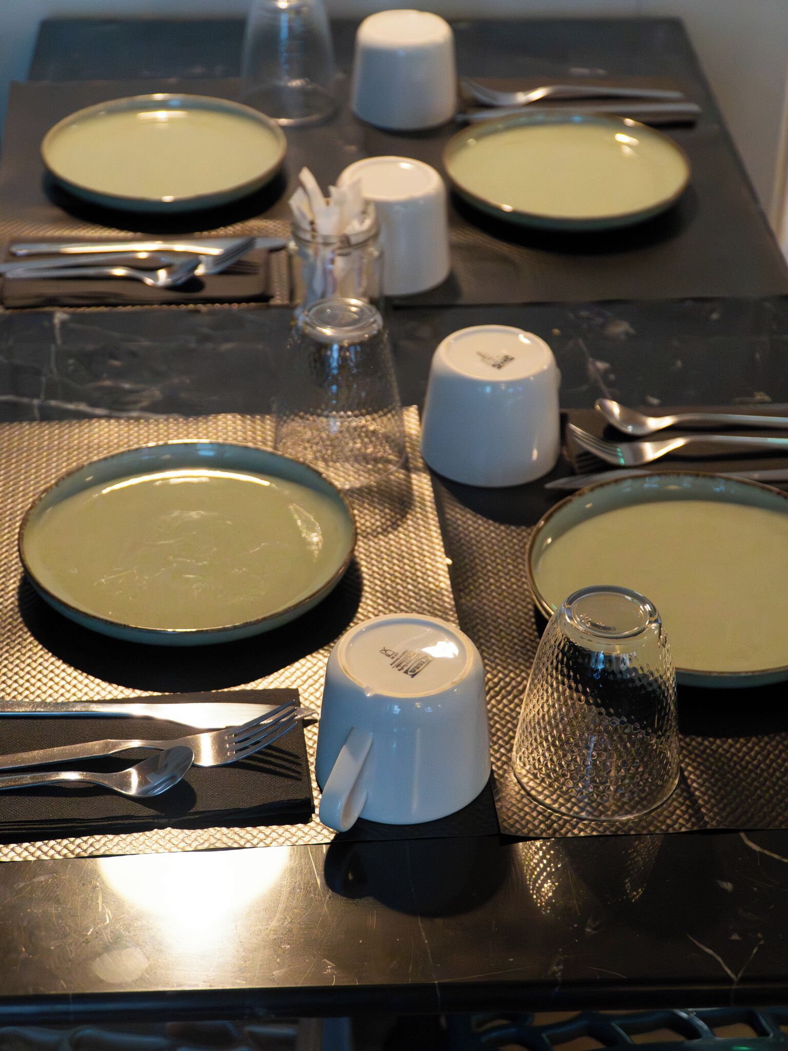 Taula de dinar preparada amb plats, coberts i vetrería, que indica un àpat a punt.