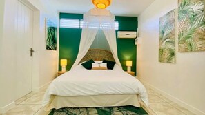 A bed with a canopy, a wall-mounted air conditioner, and two bedside lamps. - Gîtes Carambole, les Orchidées de Sainte-Anne with swimming pool, jacuzzi and garden (Sainte-Anne)
