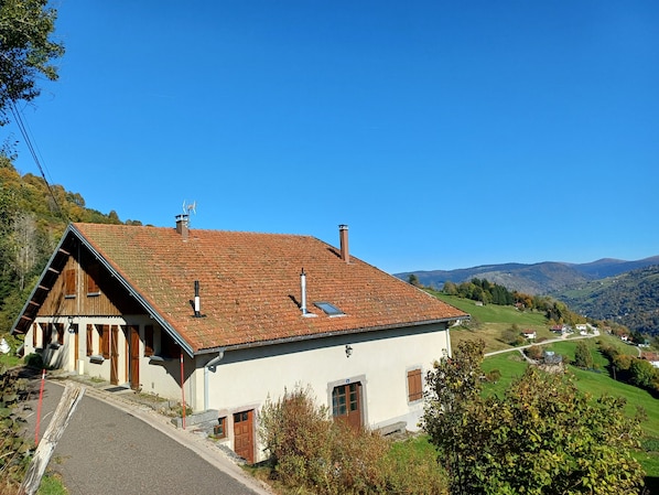 A traditional chalet with a sloped roof, wooden shutters, and a chimney.