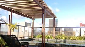 Eine Dachterrasse mit Pergola, Sitzgelegenheiten, einem kleinen Pool und Blick auf die Stadt.