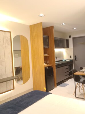 A modern kitchen with a refrigerator, microwave, and wooden cabinets. - Estudio HUB Pôr do Sol Intermares (Cabedelo)