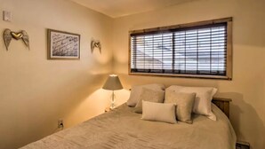 A bedroom with a bed, a nightstand, a lamp, and decorative angel wall art. - BEST LOCATION! Cozy condo on Main Street. Walk to gondola. (Breckenridge)
