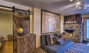 Un salón acogedor con sofá, un globo terráqueo, un mapa y una chimenea con la etiqueta 'BRECK'.