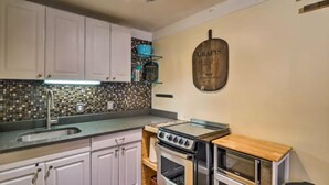 A kitchen with white cabinets, a tiled backsplash, a stove, an oven, and a microwave. - BEST LOCATION! Cozy condo on Main Street. Walk to gondola. (Breckenridge)