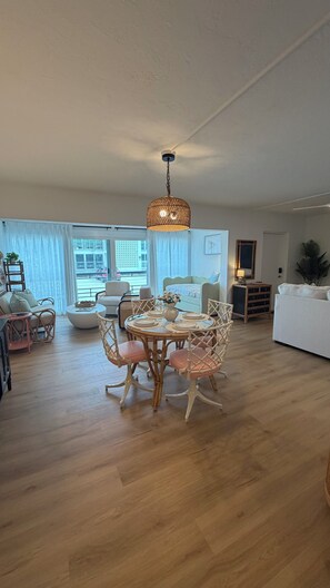 Ein geräumiges Wohnzimmer mit Essbereich, einem großen Fenster und einer hängenden Leuchte.