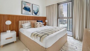 Ein modernes Hotelzimmer mit einem großen Bett, einem Holzkopfende, einem Nachttisch, einer Nachttischlampe und einem großen Fenster mit Vorhängen.