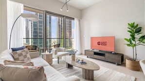 A modern living room with a sofa, coffee table, and TV. - Luxurious 1bedroom All Bills Included (Dubai)