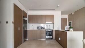A modern kitchen with wooden cabinets, a stainless steel oven, and a white countertop. - Luxurious 1bedroom All Bills Included (Dubai)