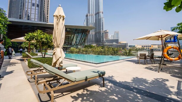 A rooftop pool area with lounge chairs, umbrellas, and a view of the Burj Khalifa. - Luxurious 1bedroom All Bills Included (Dubai)