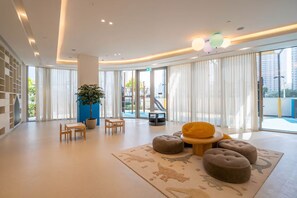 Um hall amplo com uma grande planta, área de estar e vista para o exterior.