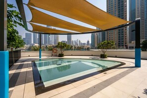 Uma piscina no terraço com vista para o horizonte da cidade, cercada por vegetação e coberta por uma grande cobertura.